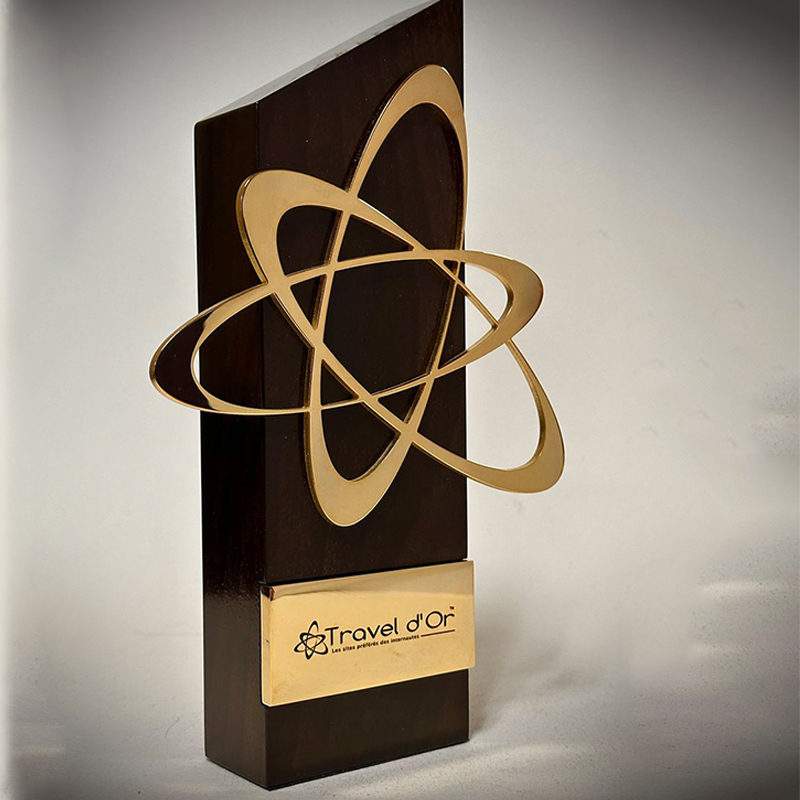 Trophée Travel d'Or en bois foncé avec motif en laiton doré représentant des orbites entrelacées et plaque personnalisée