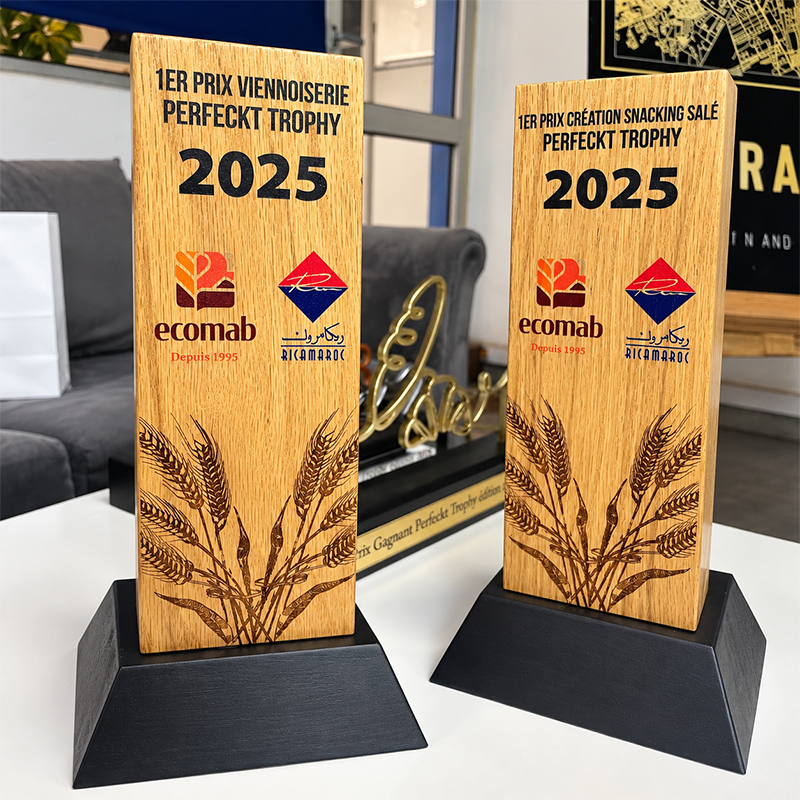 Deux trophées en bois Perfect Trophy 2025 avec motifs d'épis de blé, inscriptions des premiers prix Viennoiserie et Snacking Salé, et socles noirs