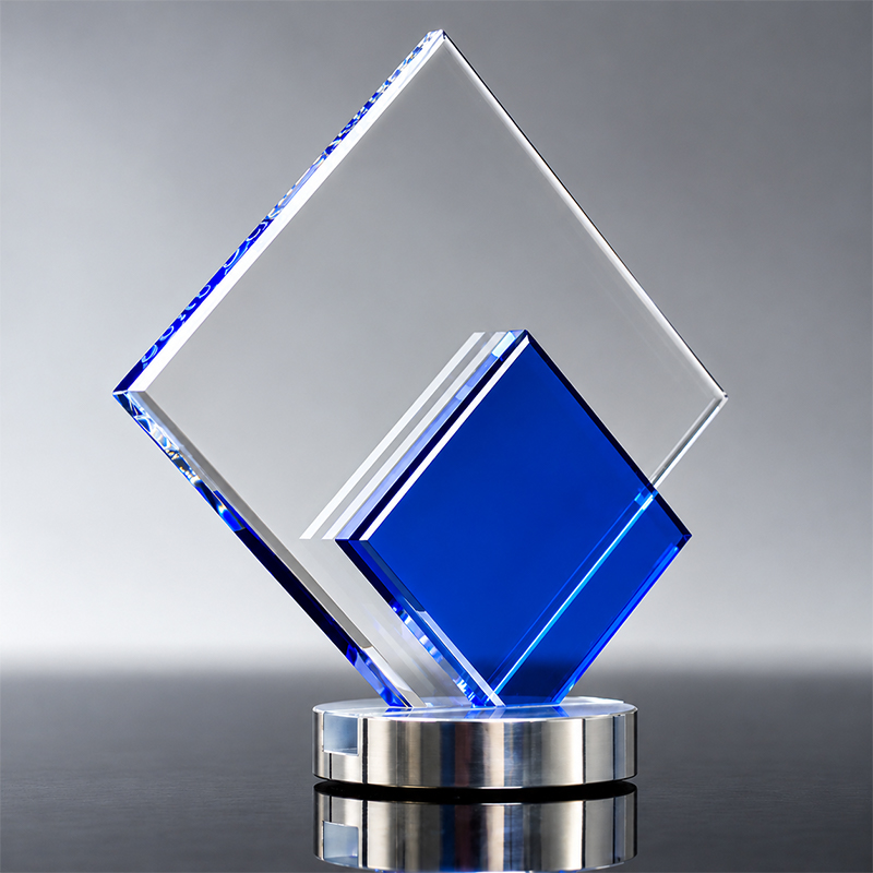 Trophée transparent composé de deux plaques géométriques superposées, dont une bleue, sur un socle circulaire argenté