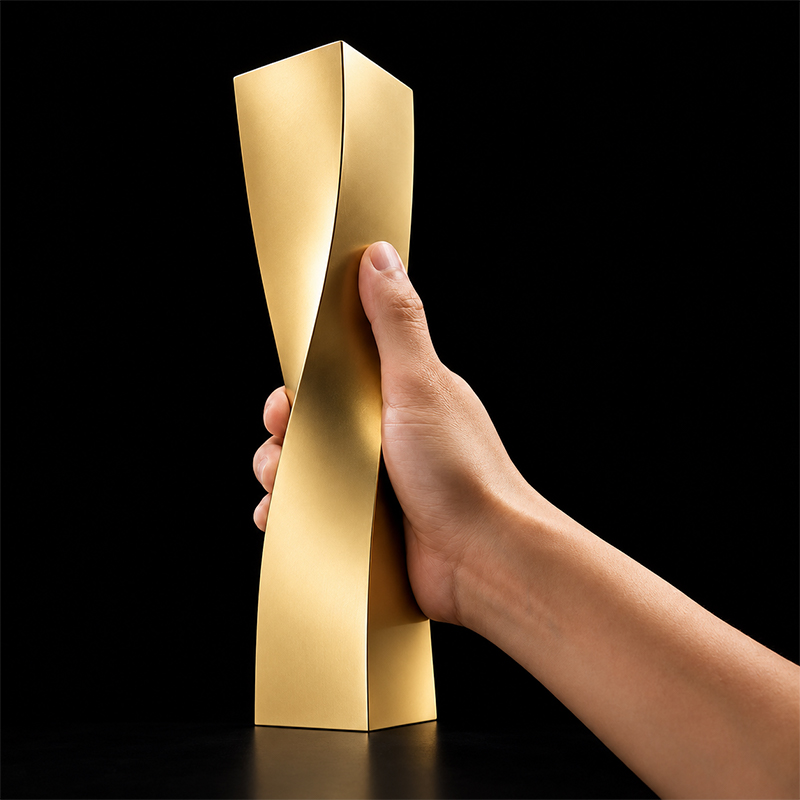 Trophée vertical doré au design géométrique torsadé, présenté à la main sur fond noir