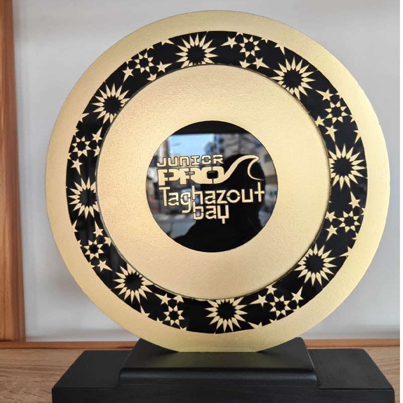 Trophée Junior Pro Taghazout Bay en métal effet doré, de forme circulaire avec motifs étoilés noirs et socle noir